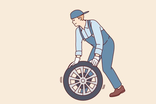 Man automobile repairman changes car wheel to new one to avoid accident or perform scheduled inspection. Employee of garage car workshop conducts vehicle maintenance or pre-sale preparation