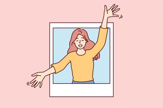 Delighted woman peeks out of photo with arms apart to hug you and give good mood. Attractive girl in casual clothes rejoices at meeting or wishes to hug goodbye