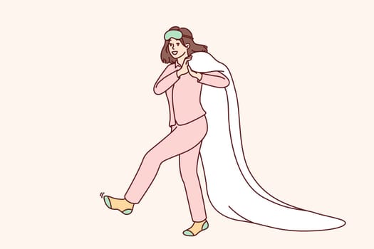 Happy woman in pajamas and socks after morning awakening walks dragging blanket behind back. Young caucasian girl in good mood goes to bed to rest after hard day work