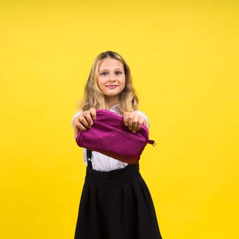 Happy schoolgirl with colored pencils and pencil case in hand