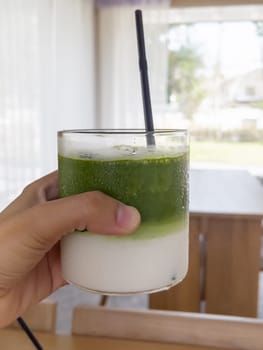 Hand holding iced matcha green tea, stock photo