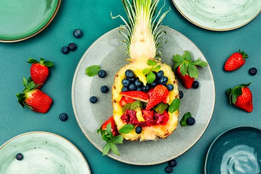 Healthy fresh fruit salad of strawberries, kiwi, berries and orange in half a pineapple.