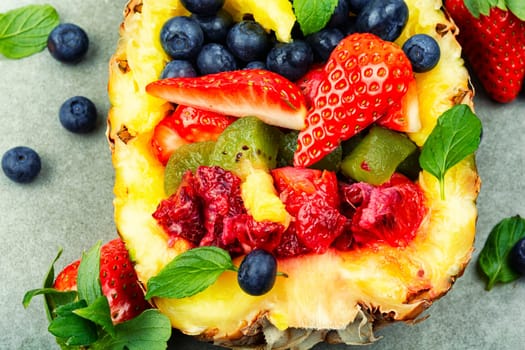 Healthy fresh fruit salad of strawberries, kiwi, berries and orange in half a pineapple.