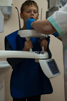 Jaw computed tomography, check up teeth in dental clinic. Boy in vest with open mouth on x-ray diagnostics. Circular snapshot of jaw on modern medical equipment. CT scanning, patient and radiologist.