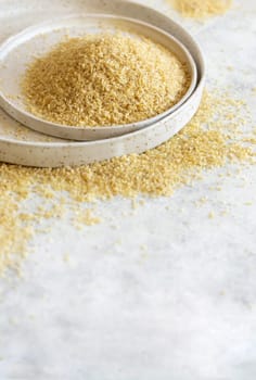 Raw Dry bulgur wheat grain on a white plate on a table close up, copy space. Vegetarian and Vegan, Mediterranean and Middle Eastern cuisine. Healthy lifestyle