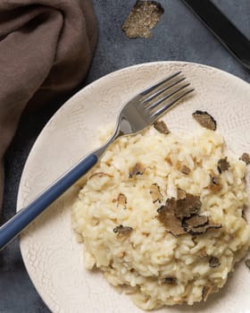 Risotto with wild porcini mushrooms and black truffles from Italy served in a plate top view on white table, copy space. Eating Italian gourmet cousine