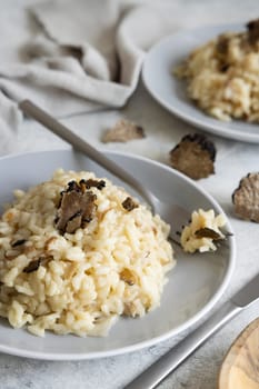 Risotto with wild porcini mushrooms and black truffles from Italy served in a plate close up on white table. Eating Italian gourmet cousine