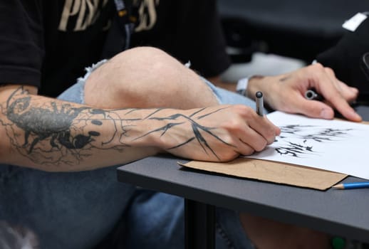 Krakow, Poland -  June 11, 2022: Unidentified  participant at 15th Tattoofest Convention in Cracow. One of the most prestigious tattoo festivals. Tattoo artist at work.