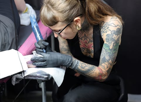 Krakow, Poland -  June 12, 2022: Unidentified  participant at 15th Tattoofest Convention in Cracow. Tattoo artist at work.