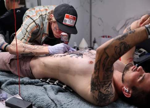 Krakow, Poland -  June 12, 2022: Unidentified  participant at 15th Tattoofest Convention in Cracow. One of the most prestigious tattoo festivals. Tattoo artist at work.
