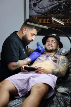 Krakow, Poland -  June 12, 2022: Unidentified  participant at 15th Tattoofest Convention in Cracow. One of the most prestigious tattoo festivals. Tattoo artist at work.