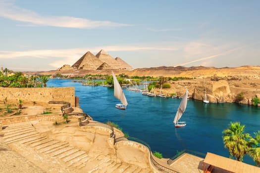 Sailboats and ancient rocks in the Nile on the way to pyramids, Aswan, Egypt.