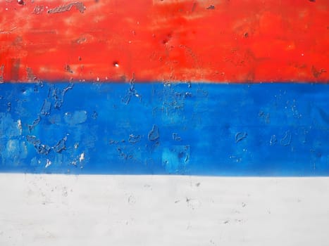 Serbian flag, tricolor red, blue, white painted on a metal surface. Peeling paint.