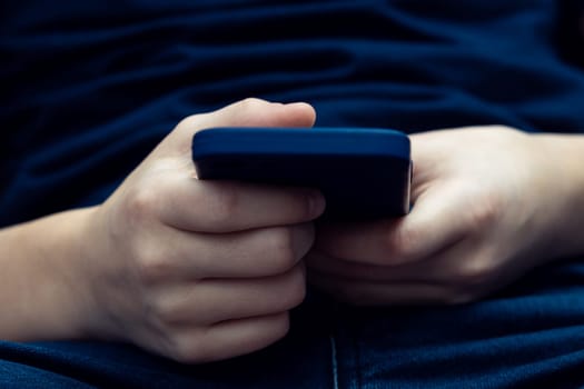 Male hands holding smartphone closeup. Young guy using mobile phone to play game, browsing media, communicate or watch online video content. Entertainment, modern gadget, digital electronics.