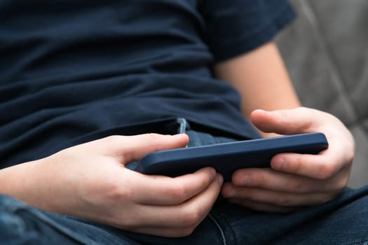 Male hands play videogames on smartphone closeup. Young guy using mobile phone to play game or watch online video content. Entertainment, modern gadget, touchscreen, digital electronics.