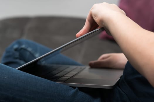 Digital laptop computer in male hands, side view closeup. Young business man close gray metal lid of portable notebook. Working on multitasking gadget. High technology, IT specialist, electronics.