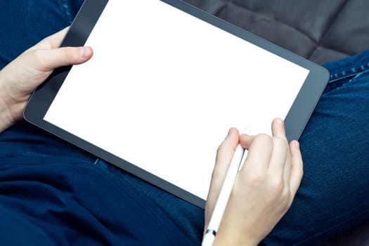 Digital tablet computer with blank white screen in male hands, from above view closeup. Business man working on modern handheld gadget with stylus. Sensory pen drawing, touchscreen, electronics.