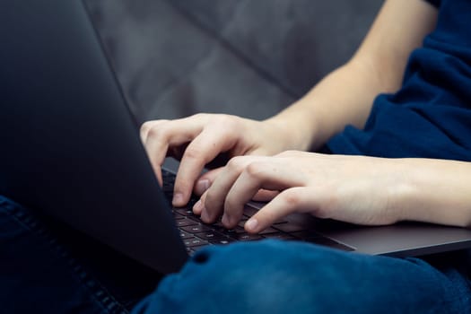 Digital laptop computer on male legs closeup. Young business man typing on keyboard of portable modern notebook. Working on multitasking gadget, high technology, IT sphere, electronics.