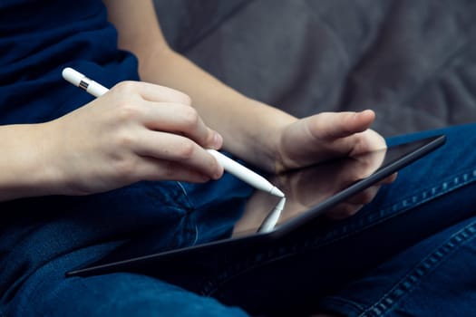Digital tablet computer in male hands, side view closeup. Young business man work on multitasking handheld gadget with stylus. Sensory pen drawing and writing, touchscreen, electronics.