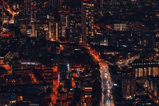 Night aerial view of south west London, orange yellow street lights glowing, small cars visible on main road.