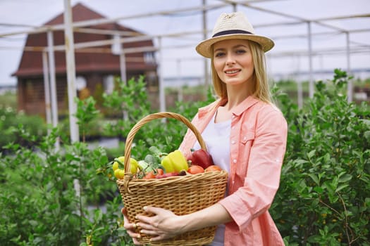 Young gardener with basket of fresh vegs looking at camera