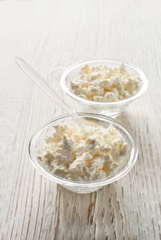 Fresh cottage cheese in a bowl on a wooden background