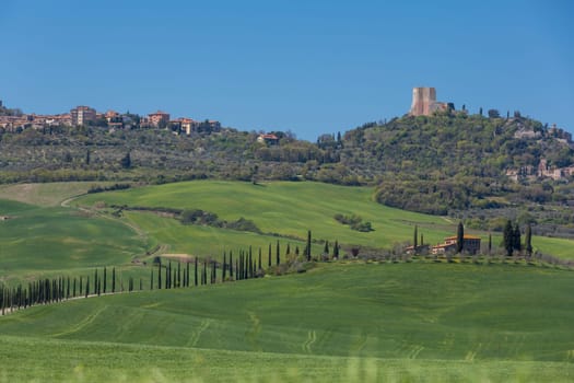 A Tuscan farmhouse in front of a village with a ruin