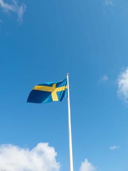 Swedish flag blowing in the wind on the blue sky