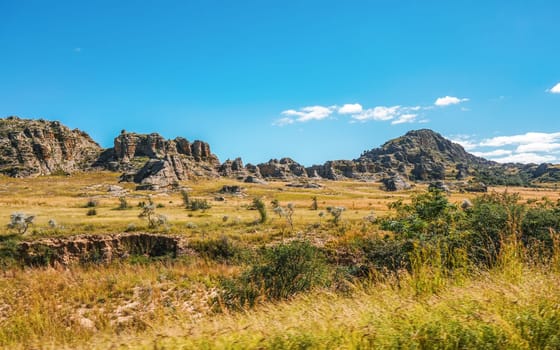 Low grass growing on African savanna, small rocky mountains in background - typical scenery at Isalo national Park, Madagascar.
