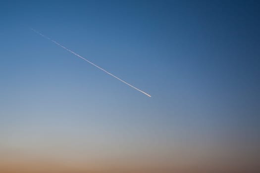 The trace of the plane in the sky, in the clear evening sky remained the trace of the flying plane in the distance