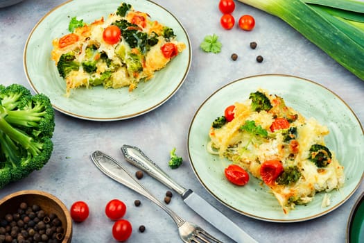 Appetizing potato casserole with broccoli and tomatoes on a plate.