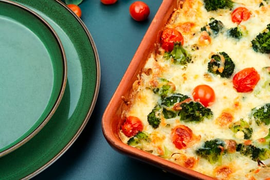 Appetizing potato casserole with broccoli and tomatoes on a plate.