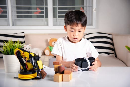 Happy Asian little boy using remote control playing robotic machine arm for pick up wood block, Funny learning successful getting a lesson control robot arm, Technology science education concept