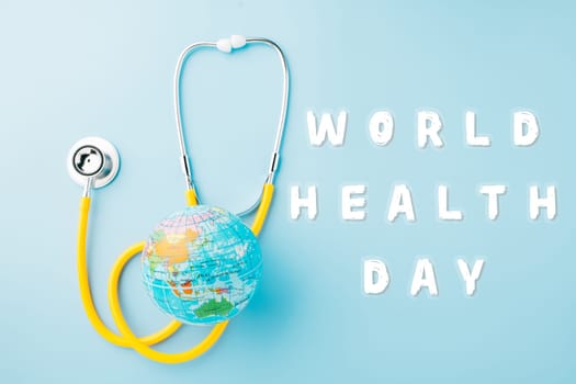 World Health Day. Yellow doctor stethoscope and world globe isolated on blue background, Save world day, Green Earth, Healthcare and medical concept