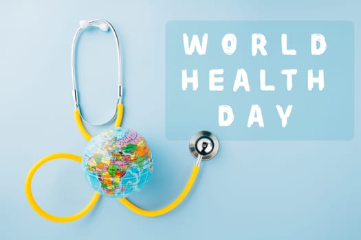 World Health Day Concept. Top view yellow doctor stethoscope and world globe isolated on pastel blue background with copy space, Save world day, Environment Green Earth, Health care and medical