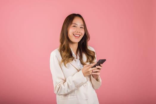 Female surprised and sms chatting internet online on smartphone studio shot isolated on pink background, Happy Asian portrait beautiful cute young woman teen smiling excited hold smart mobile phone