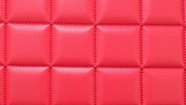 The surface texture of artificial leather in red, stitched in the form of rhombuses, squares, rectangles. Quilted eco-leather. High quality photo