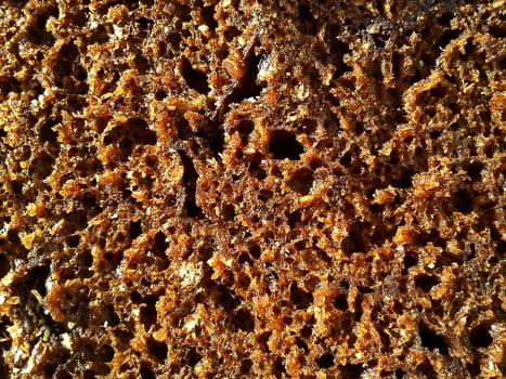 brown rye bread close-up. Healthy food with vitamins, minerals, bran and seeds. High-quality baked bakery product. Loose, with pores and holes material.