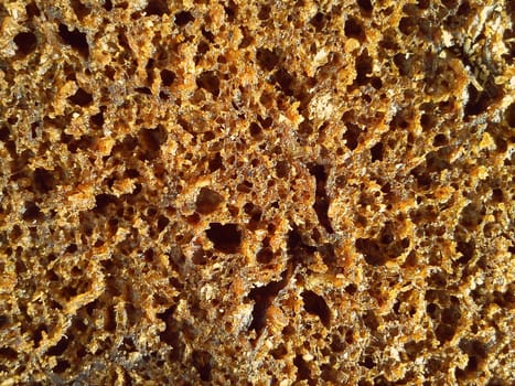 brown rye bread close-up. Healthy food with vitamins, minerals, bran and seeds. High-quality baked bakery product. Loose, with pores and holes material.