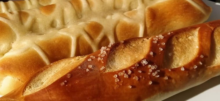 Delicious appetizing freshly baked fatty wheat buns sprinkled with salt and salted gravy. Close-up. White bread containing gluten, many calories and carbohydrates. Quick everyday breakfast. Diabetes.