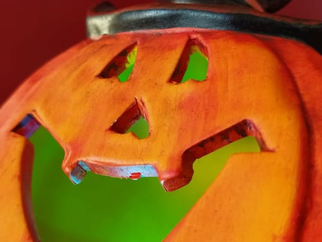 Bright orange Halloween pumpkin. Cut holes for mouth, nose and eyes. Green scary glow from the inside of the pumpkin. Close-up. The sinister laugh of the monster. Blurring the edges of the image.