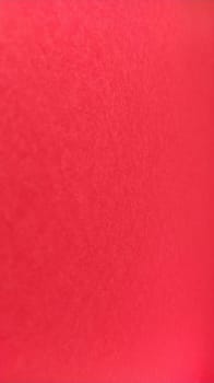 Beautiful vertical red bright background. Scarlet color. A rough sheet of colored paper with natural light. Fragment of a sheet of colored paper with a thin fleecy surface