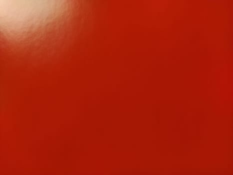 Beautiful bright red background. Closeup sheet of shiny reflecting incident light paper. Pure fun color. Intense shade of red, close to scarlet or blood color with high reflectivity