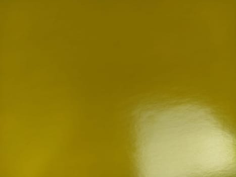 Nice yellow background. A sheet of paper close-up. Pure cheerful color. Bright shade of yellow, close to a dark color with shine. Reflection of light on a shiny surface.