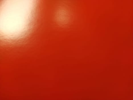 Beautiful bright red background. Closeup sheet of shiny reflecting incident light paper. Pure fun color. Intense shade of red, close to scarlet or blood color with high reflectivity