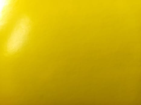 Beautiful bright yellow background. Close-up sheet of shiny reflective incident light paper. Pure fun color. Intense shade of yellow, close to gold or sunny with high reflectivity