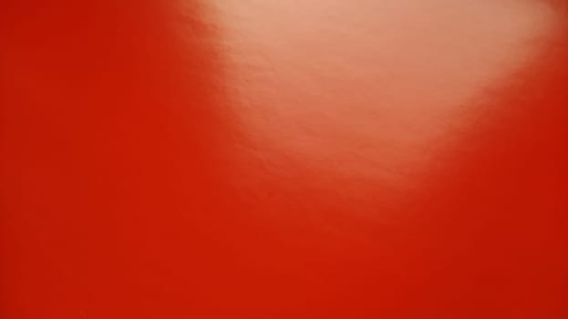 Beautiful bright red background. Closeup sheet of shiny reflecting incident light paper. Pure fun color. Intense shade of red, close to scarlet or blood color with high reflectivity
