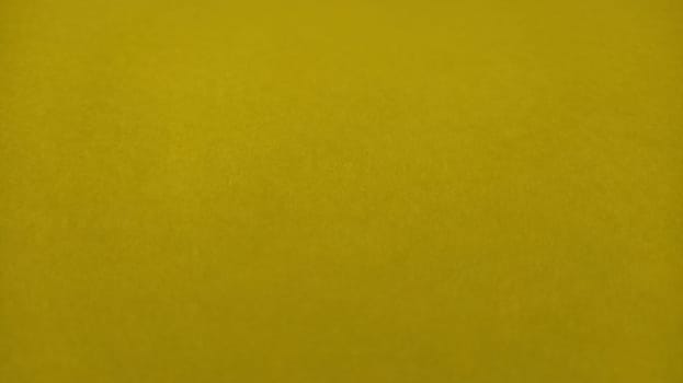 The paper or fabric is bright yellow. Close-up. Lightly folded sheet. Light gradient and accentuated rough surface texture. Background or product sample. Sunny cheerful yellow. Copy space.
