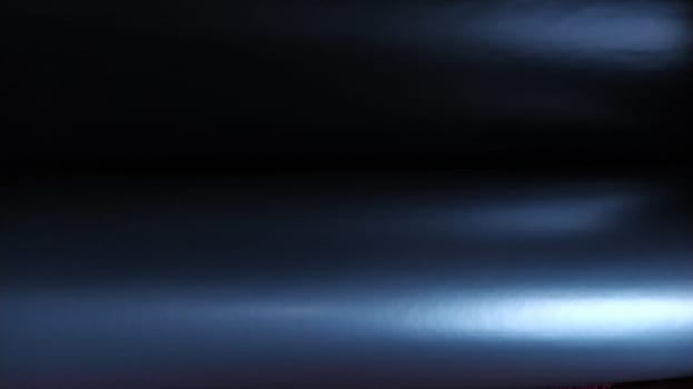 Gradient on a blue-violet background. Horizontally folded shiny paper or foil with overflow and highlights. Mysterious radiance. Luxurious fabric. Metallic cold shine