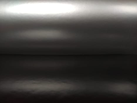 Gradient on a gray-black background. Horizontally folded shiny paper or foil with overflow and highlights. Mysterious radiance. Luxurious fabric. Metallic cold shine